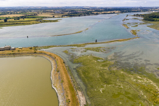 Aerial view of the Boyne Estuary with marshlands, a stone embankment, and green fields in the distance near Baltray, County Louth, Ireland.