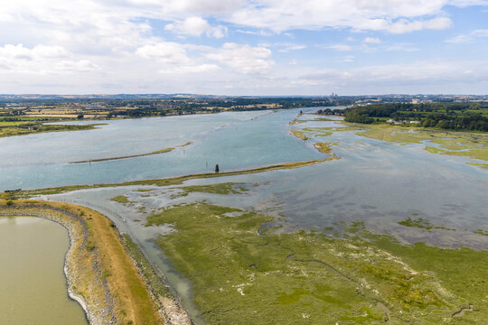 Aerial view of the Boyne Estuary with its winding waterways, marshy banks, and green coastal landscape under a bright sky in Baltray, County Louth, Ireland.