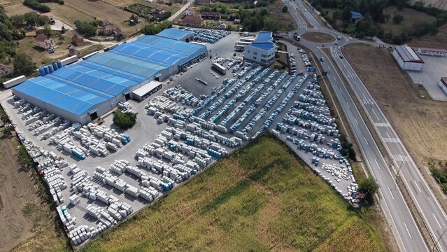 Aerial view of a large industrial warehouse facility with rows of portable units stored in the yard, situated near a highway junction in Kragujevac, Sumadija District, Serbia.