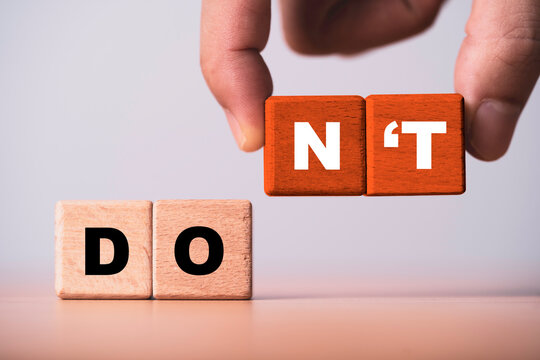 Hand arranging wooden blocks from DO to DON'T representing decision making, warning prohibition, behavioral change, risk avoidance, business choices, rules and responsible action concept.