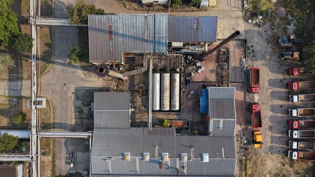 Aerial view of an industrial oil refinery complex featuring metal-roofed buildings, storage tanks, complex piping systems, and a row of parked trucks in Belgrade, City of Belgrade, Serbia.