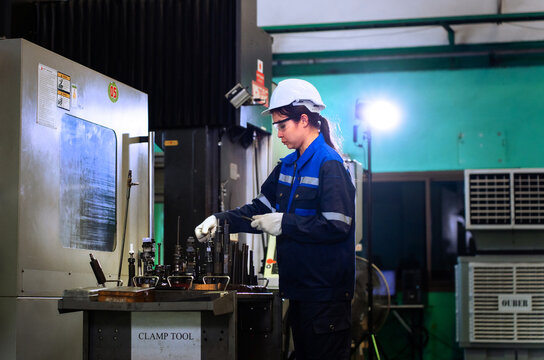 Female industrial worker selecting precision tools beside cnc machinery in manufacturing factory.	