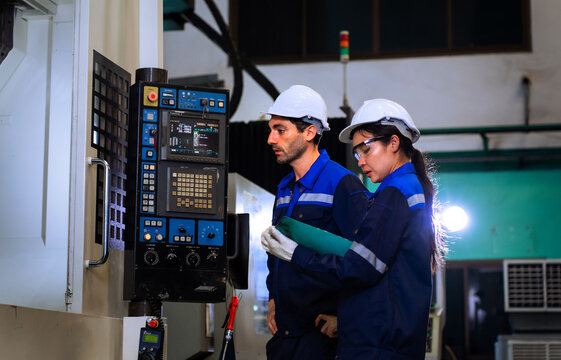 Industrial engineers inspecting cnc machine operation with clipboard in modern factory. ideal for manufacturing, automation, and industry 4.0 marketing campaigns.