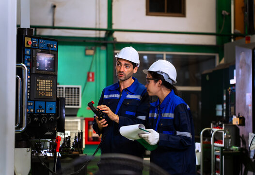 Factory workers reviewing clipboard checklist near industrial machinery in manufacturing plant. ideal for industrial quality control, team engineering, and manufacturing concepts.