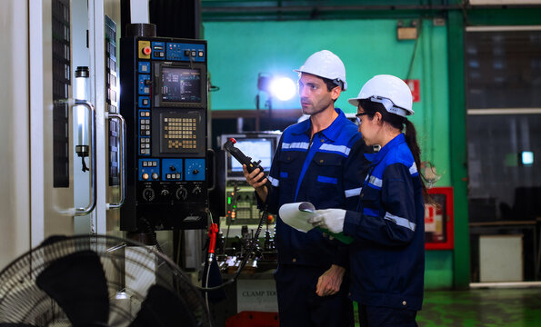 Factory workers reviewing clipboard checklist near industrial machinery in manufacturing plant. ideal for industrial quality control, team engineering, and manufacturing concepts.