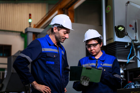 Industrial engineers inspecting cnc machine operation with clipboard in modern factory. ideal for manufacturing, automation, and industry 4.0 marketing campaigns.