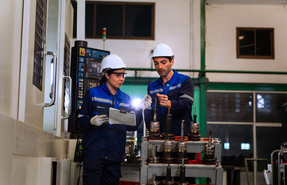 Industrial engineers inspecting cnc machine operation with clipboard in modern factory. ideal for manufacturing, automation, and industry 4.0 marketing campaigns.