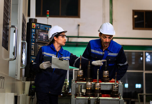 Industrial engineers inspecting cnc machine operation with clipboard in modern factory. ideal for manufacturing, automation, and industry 4.0 marketing campaigns.