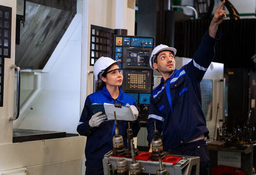 Industrial engineers inspecting cnc machine operation with clipboard in modern factory. ideal for manufacturing, automation, and industry 4.0 marketing campaigns.