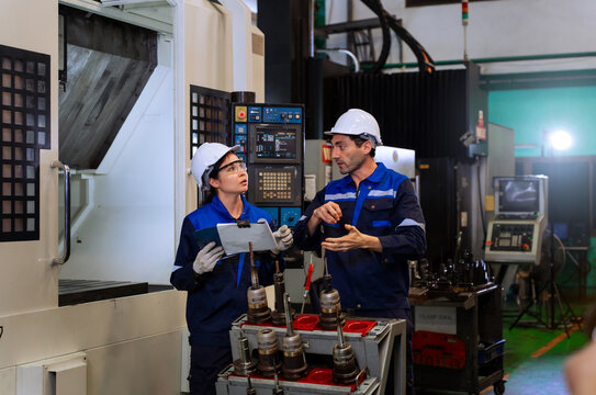 Industrial engineers inspecting cnc machine operation with clipboard in modern factory. ideal for manufacturing, automation, and industry 4.0 marketing campaigns.