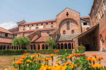 Fototapeta premium Abbaye de Staffarda avec cloître roman et fleurs orangées, Piémont