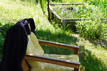 Wooden garden armchair with fleece jacket near raised vegetable beds © Yuliia