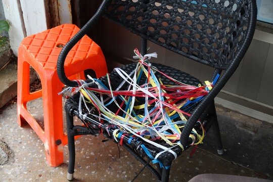 Frugal DIY life hack - hole in chair seat repaired with random pieces of string and ribbons. DIY ingenuity in Kenting, Taiwan.