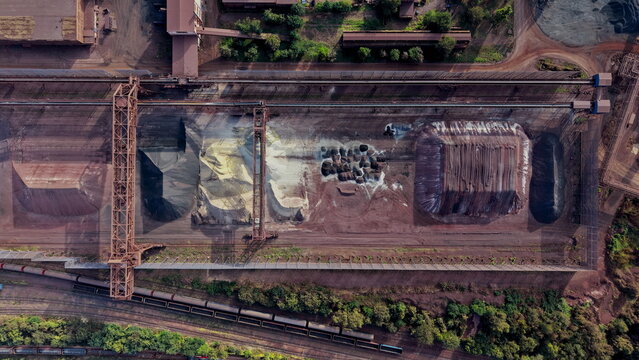 Aerial view of Smederevo Steelworks featuring large piles of raw industrial materials, conveyor systems, and railway tracks in Smederevo, Podunavlje District, Serbia.
