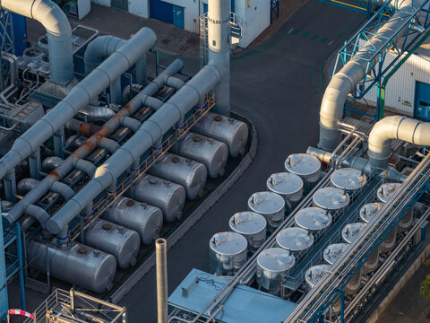 Aerial view of industrial infrastructure with rows of metallic storage tanks and complex piping systems in a manufacturing plant in Genk, Flanders, Belgium.