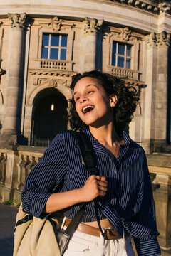Curly-haired traveler enjoys a sunny day in Berlins vibrant streets