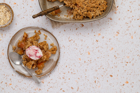 Apple oat crumble with ice cream on terrazzo table
