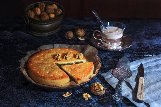 Engadine Walnuts Torte or Buendner Nusstorte on glass plate with milk tea, a Swiss confectionery spacialty in Grisons - dark and moody
