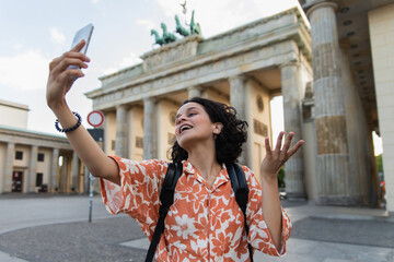 Fototapeta premium Curly-haired traveler enjoying Berlin at the iconic Brandenburg Gate