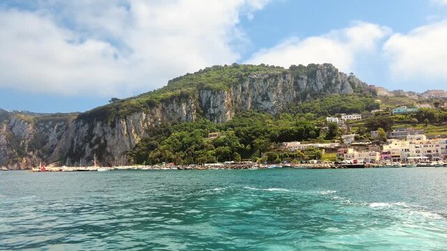 Scenic view of colorful harbor houses on capri island coastline from moving boat.
