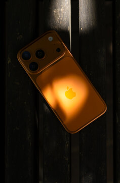 KYIV, UKRAINE - July 10, 2026 : Apple iPhone 17 Pro in Cosmic Orange color on wooden background in sunlight on logo.