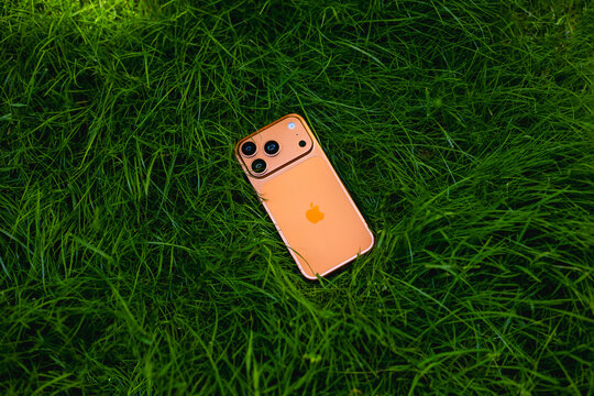 KYIV, UKRAINE - July 10, 2026 : Apple iPhone 17 Pro in Cosmic Orange color on fresh green grass outdoors.