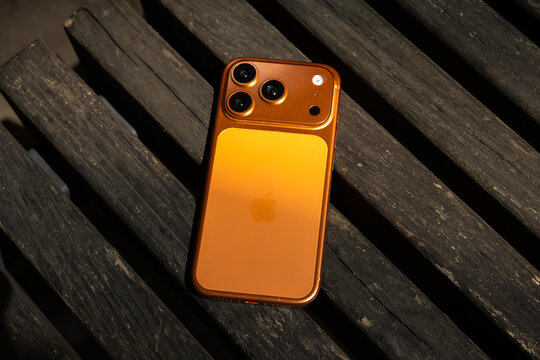 KYIV, UKRAINE - July 10, 2026 : Apple iPhone 17 Pro in Cosmic Orange color on wooden background outdoor.
