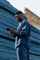 Obraz premium Man reading tablet outdoors against blue painted lumber wall for construction communication background banner and on site management design