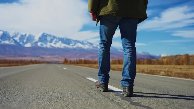 Person walks alone on empty road. Mountains rise in background under blue sky. Journey, freedom, adventure, solitude, or travel themes. Ideal for travel, exploration, or personal growth concepts
