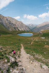 Fototapeta premium Randonneurs sur sentier de montagne face à un lac alpin, Queyras