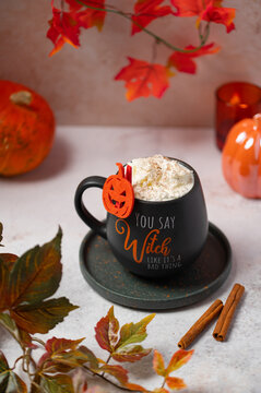 Halloween pumpkin spice latte with whipped cream and autumn leaves