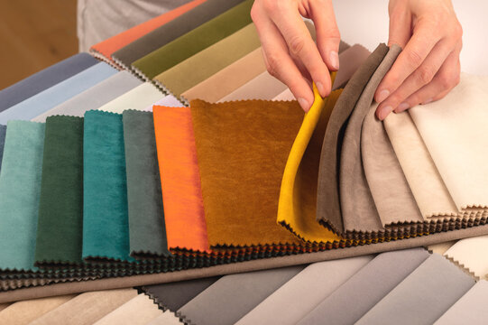 Upholstery material swatch palette for custom sofa production. Hands holding beige and brown fabric