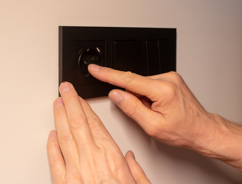 Wall socket frame cover installation on electrical outlet panel. Hands of technician placing black