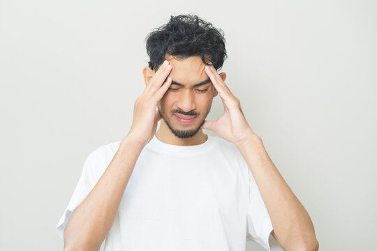 Dizzy asian young man, male headache or migraine pain suffering from vertigo or sick, holding head with hand, health problem of brain or inner ear not balance, standing isolated on white background.
