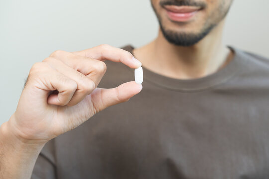 Sick asian young man, male holding tablet pill on hand, painkiller medicine from fever, stomach pain, headache for treatment, take drug, vitamin. Isolated on white background. Health care concept.