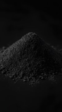 Pile of black charcoal powder on dark surface.