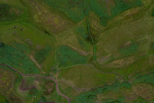 Aerial view of The Fairy Glen, featuring rolling green hills, winding paths, and grassy terrain, Uig, Scotland, United Kingdom.
