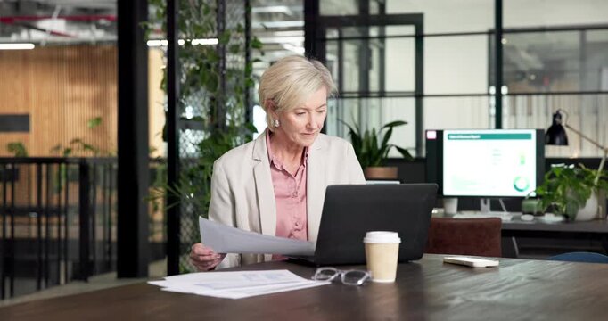Business, woman and document in office with laptop, research and finance analysis for accounting. Mature person, paperwork and comparison in workplace with pc, financial report and revenue analytics