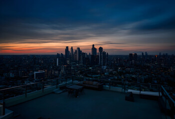 Fototapeta premium Urban skyline at sunset, city life and modern architecture, rooftop view with dramatic sky and illuminated buildings