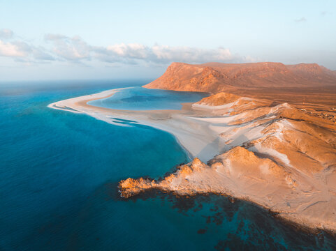 Aerial view of Detwah Lagoon Ramsar Site with its white sandbar, turquoise waters, and rugged coastal cliffs in Socotra, Yemen.