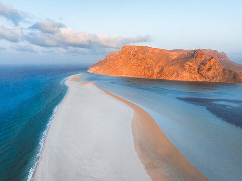 Aerial view of Detwah Lagoon Ramsar Site with its white sand spit, turquoise waters, and rocky mountains in Socotra, Yemen.