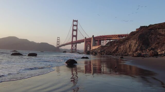 Aerial view of the Golden Gate Bridge from Baker Beach in San Francisco, California, overlooking the Pacific Ocean, rugged coastline and iconic bridge architecture, 4k.