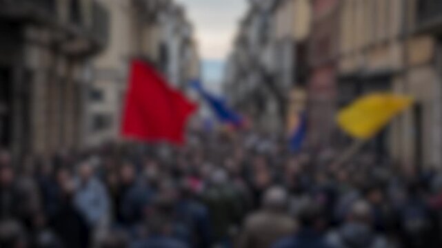 Blurred, anonymous crowd of people protesting and marching through a European city street holding flags