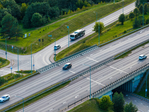 Aerial view of a highway interchange with cars and a bus driving along the road surrounded by green embankments in Vilnius, Vilnius County, Lithuania.