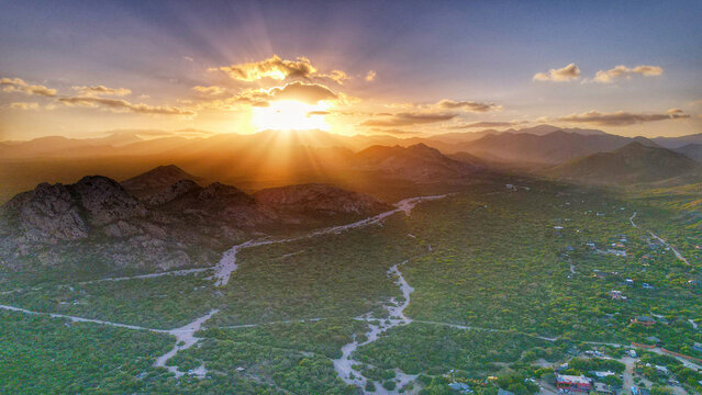 Aerial view of Parque Nacional Cabo Pulmo at sunset with sun rays over the rugged mountains and lush desert landscape Cabo Pulmo, Baja California Sur, Mexico.