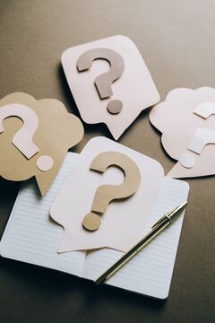 Artistic paper cutouts of question marks creating a conceptual design on a brown surface.