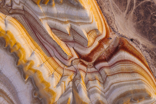 Aerial view of the colorful striped rock formations of Tiramisu Hills with intricate geological patterns and eroded ridges in the desert landscape of Kyzylkum, Mangystau Region, Kazakhstan.