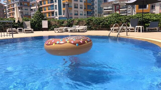 Action shot of a little girl diving into a swimming pool through an inflatable donut swim ring on a hot sunny day