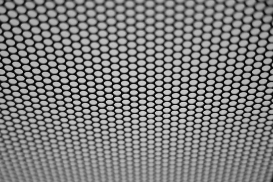 Beige perforated metal surface with circular hole grid, shallow depth of field, clean minimal industrial abstract background Black and white perforated metal iron mesh backdrop
