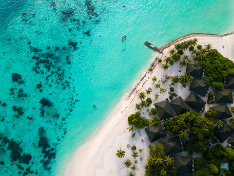 Aerial view of Meedhupparu island resort featuring overwater bungalows, white sandy beach, and turquoise lagoon, Raa Atoll, Maldives.
